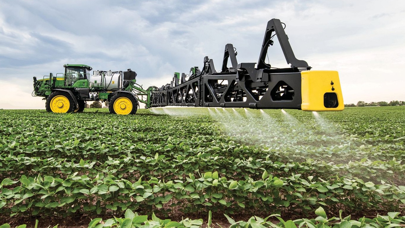Vista detalhada de uma barra de pulverização John Deere num campo aberto.