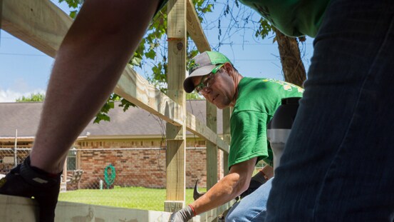 Duas pessoas a construírem uma vedação juntos perto de um edifício.