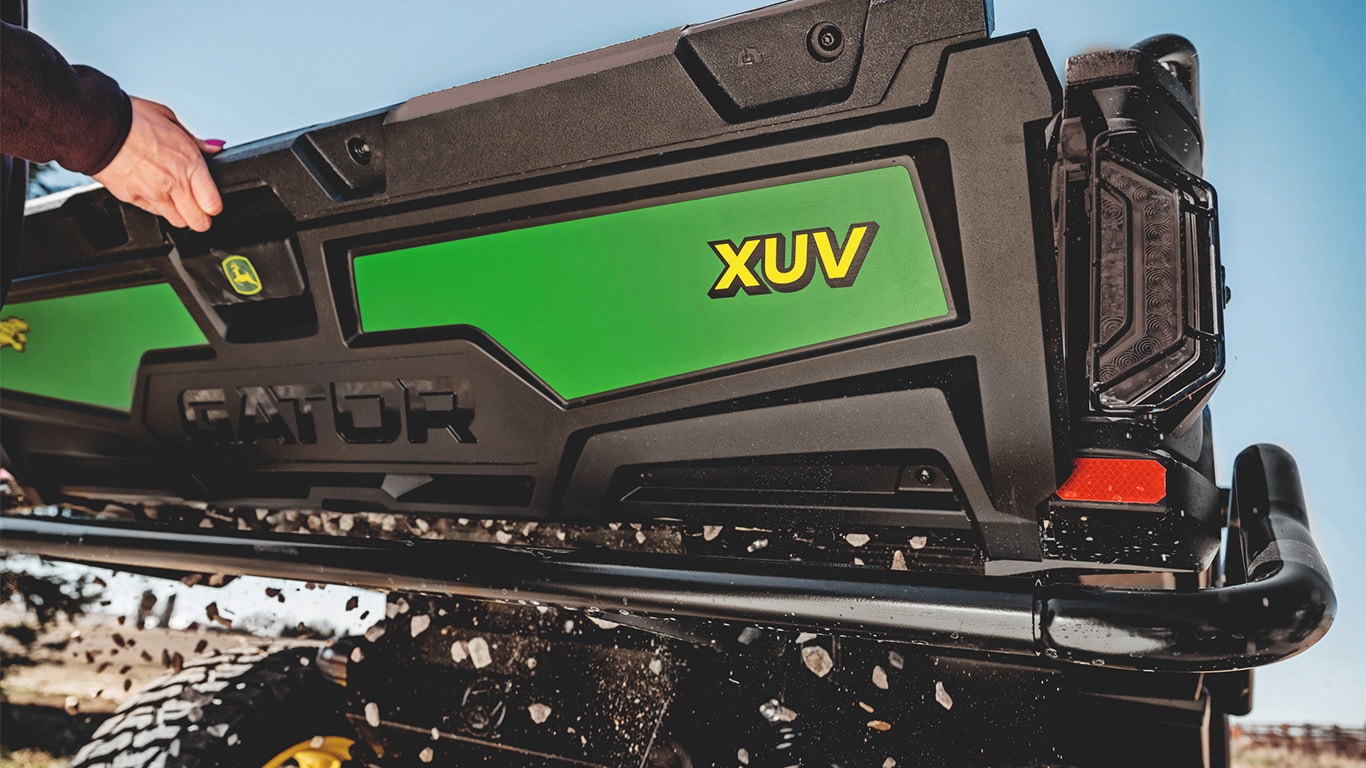 Cascalho a cair pela abertura do portão traseiro de um Gator™ XUV 875M
