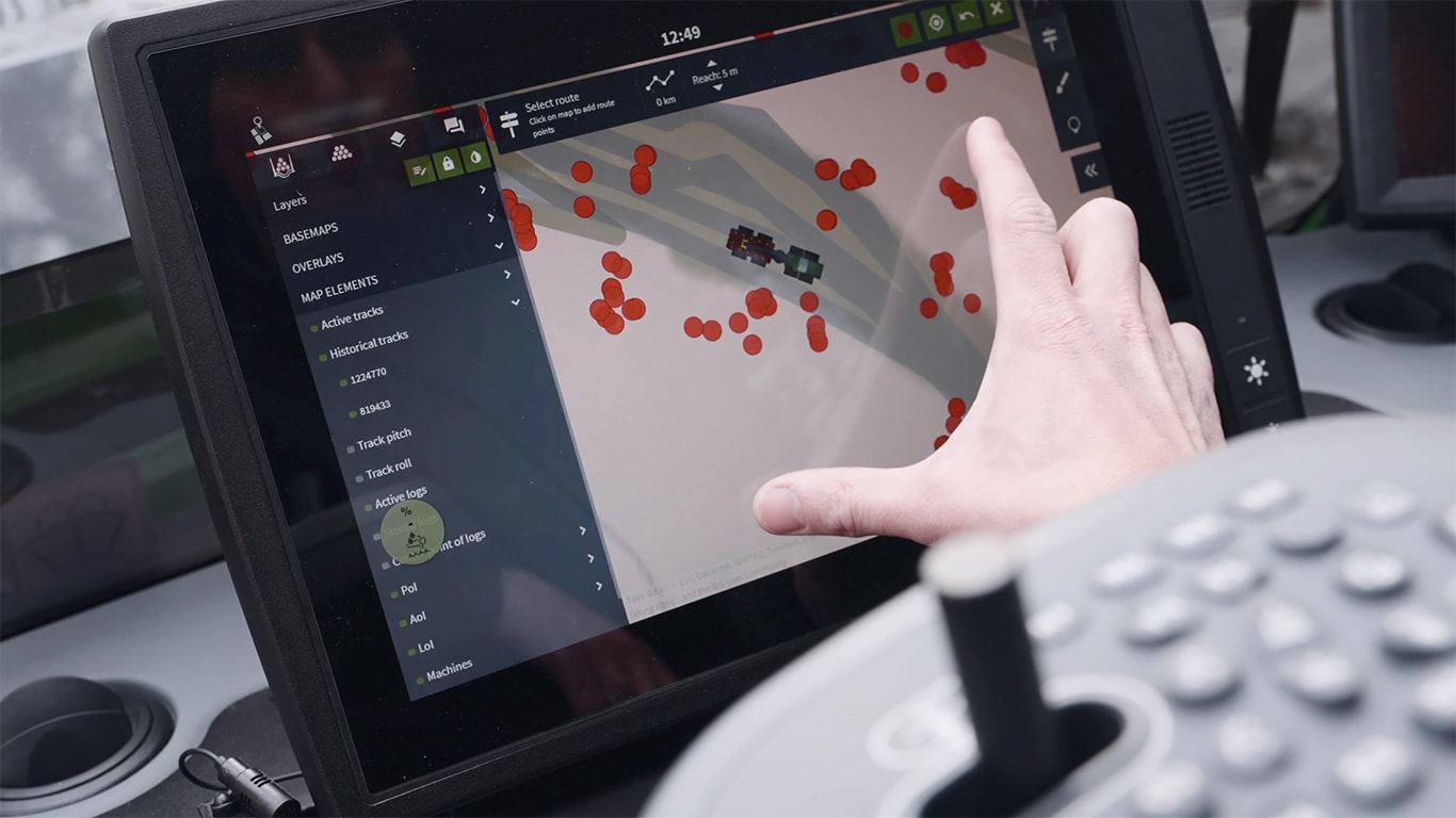 Ecrã do Mapas TimberMatic da John Deere e uma mão