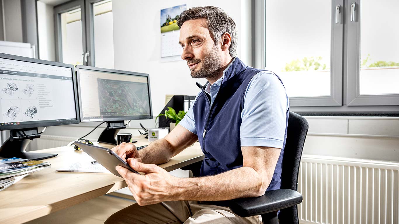 Um supervisor de greenkeepers está a usar o tablet no escritório.