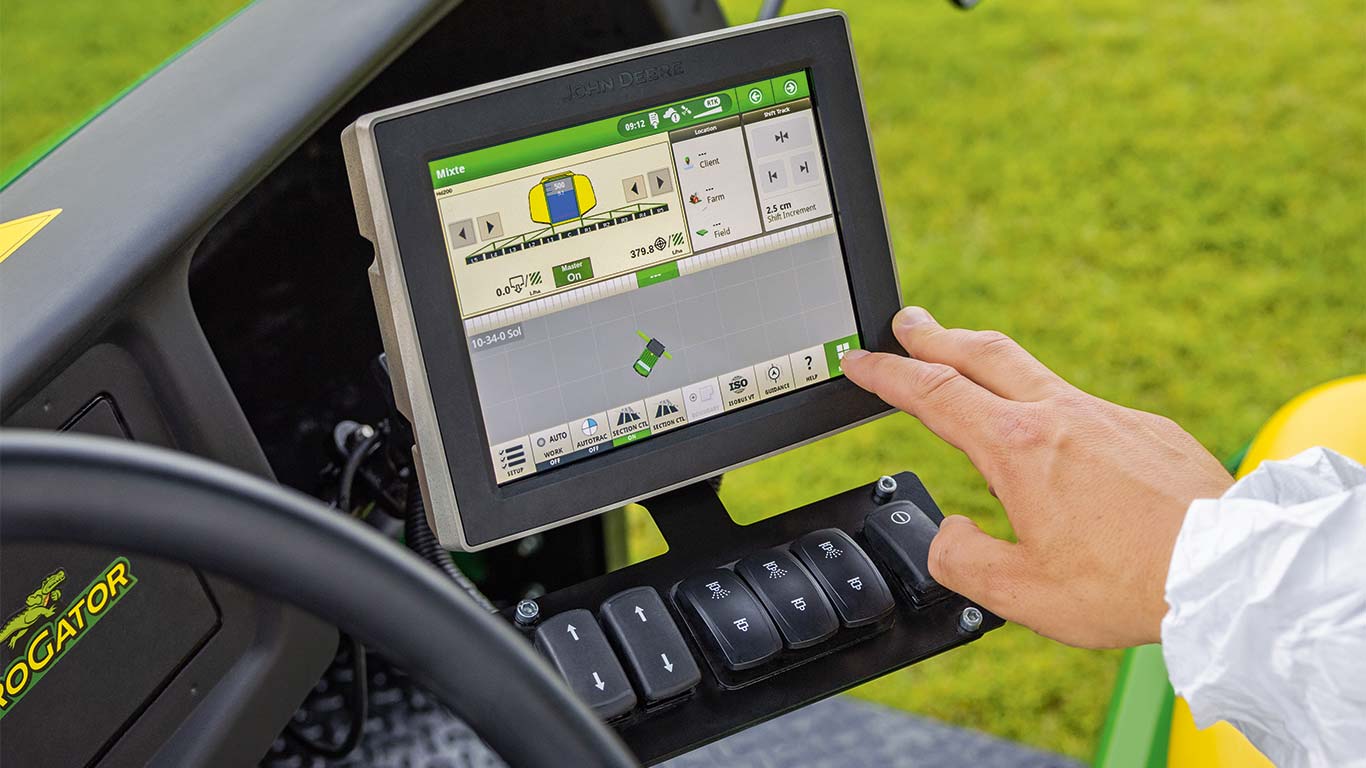 Um greenkeeper está a utilizar o monitor do seu cortador de relva John Deere para ajustar a máquina à tarefa que pretende executar.