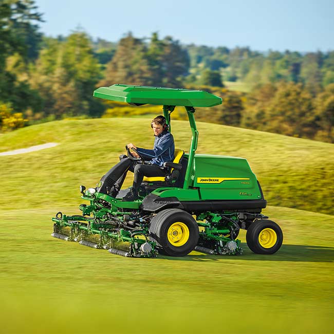 Um greenkeeper está a utilizar um cortador de relva para fairways da John Deere numa área de relva