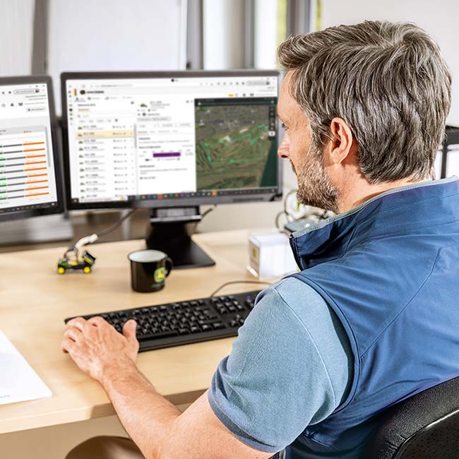 Um supervisor de greenkeepers senta-se no seu escritório e analisa os dados recolhidos pela tecnologia inteligente de manutenção de greens.